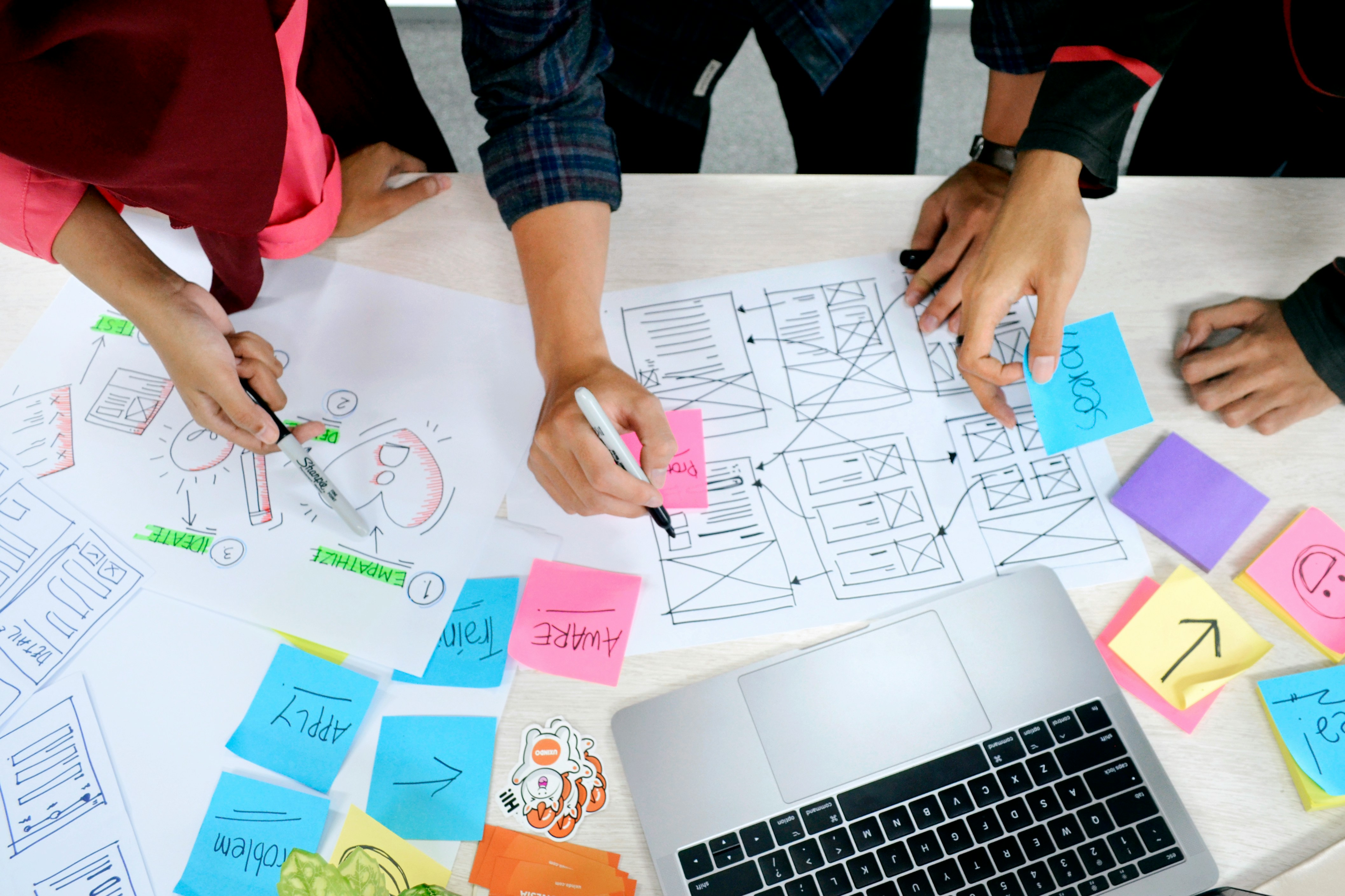Startup team collaborating with a UX/UI designer to map user journeys and design an intuitive product interface.